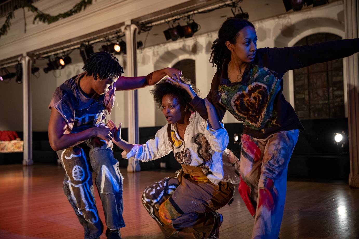 Three performers connected through touch look out, toward, and away.